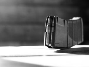 Black and white close-up of a firearm magazine with visible ammunition, emphasizing detail.
